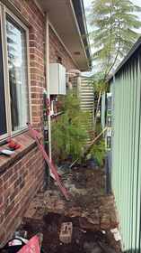 Garden bed edging and drainage preparation along a home's side yard